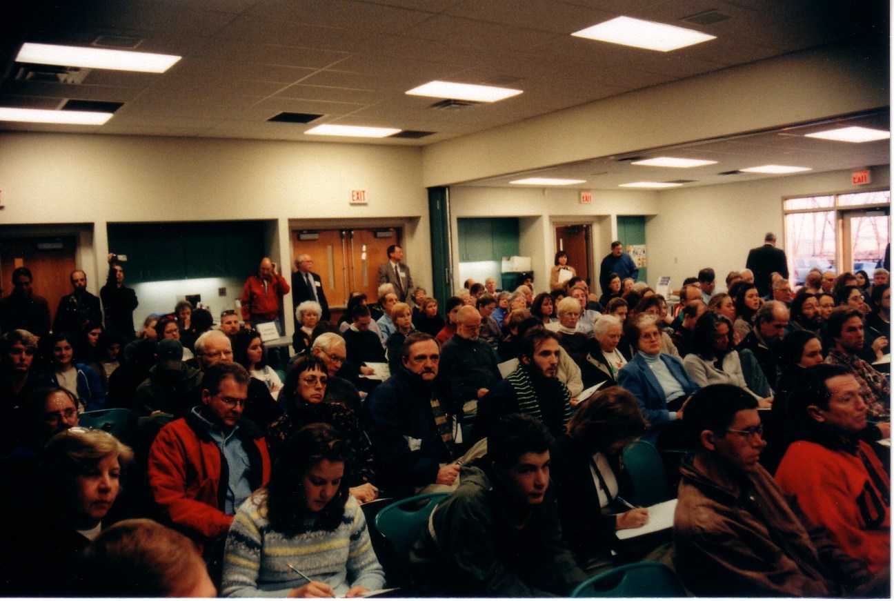a photo of a packed meeting room full of attendees looking on